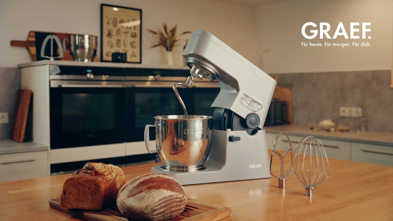 Graef Küchenmaschine mit Brot und Zubehör auf Holztisch.