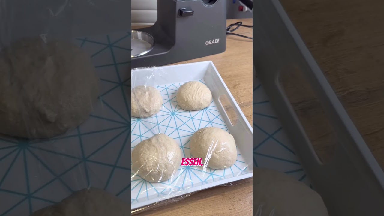 Dough balls in a tray covered with plastic wrap, GRAEF appliance in the background.