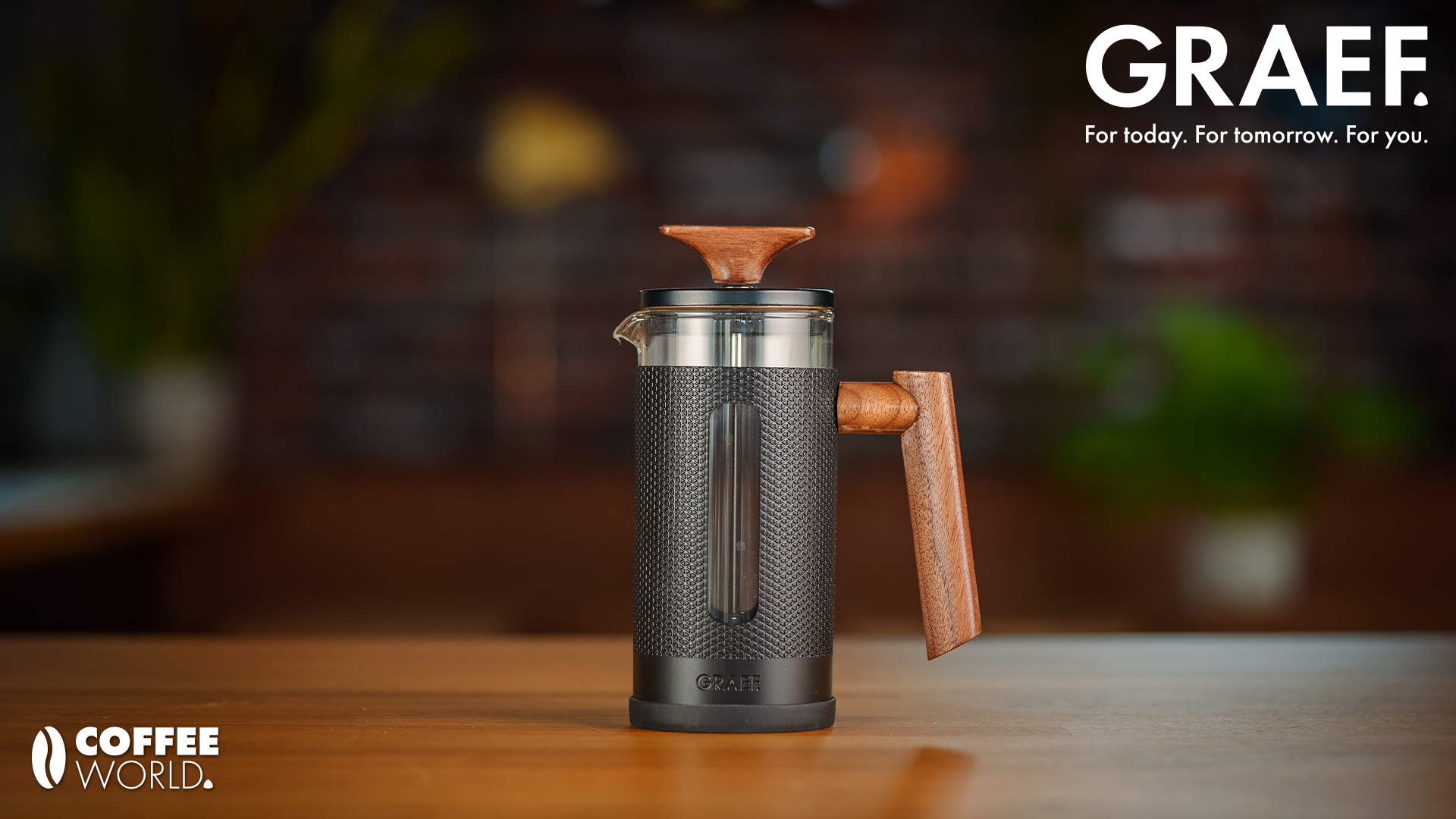 Coffee maker with wooden handle and logo on the table.