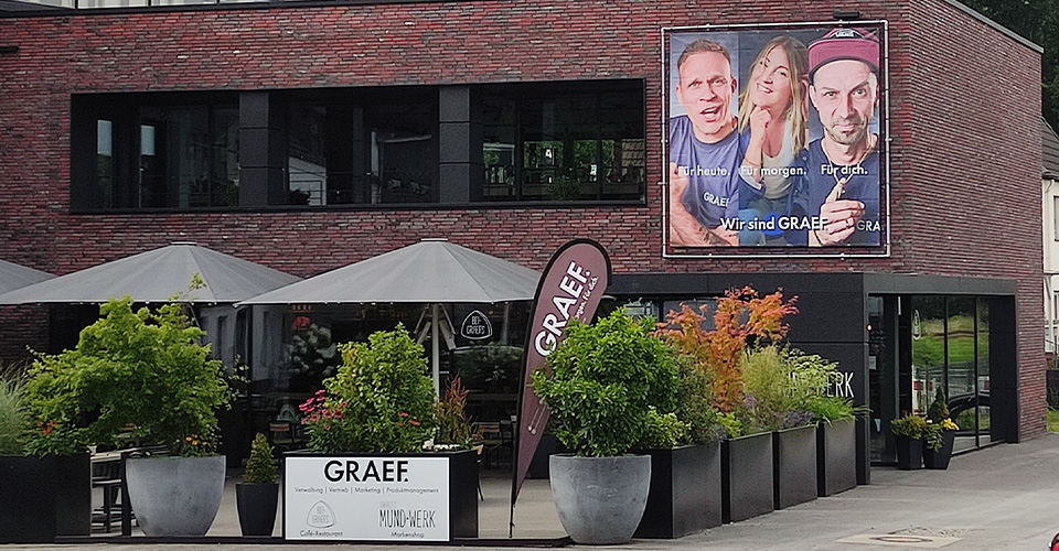 Gebäude mit Werbung für GRAEF, Restaurant und Mund-Werk.