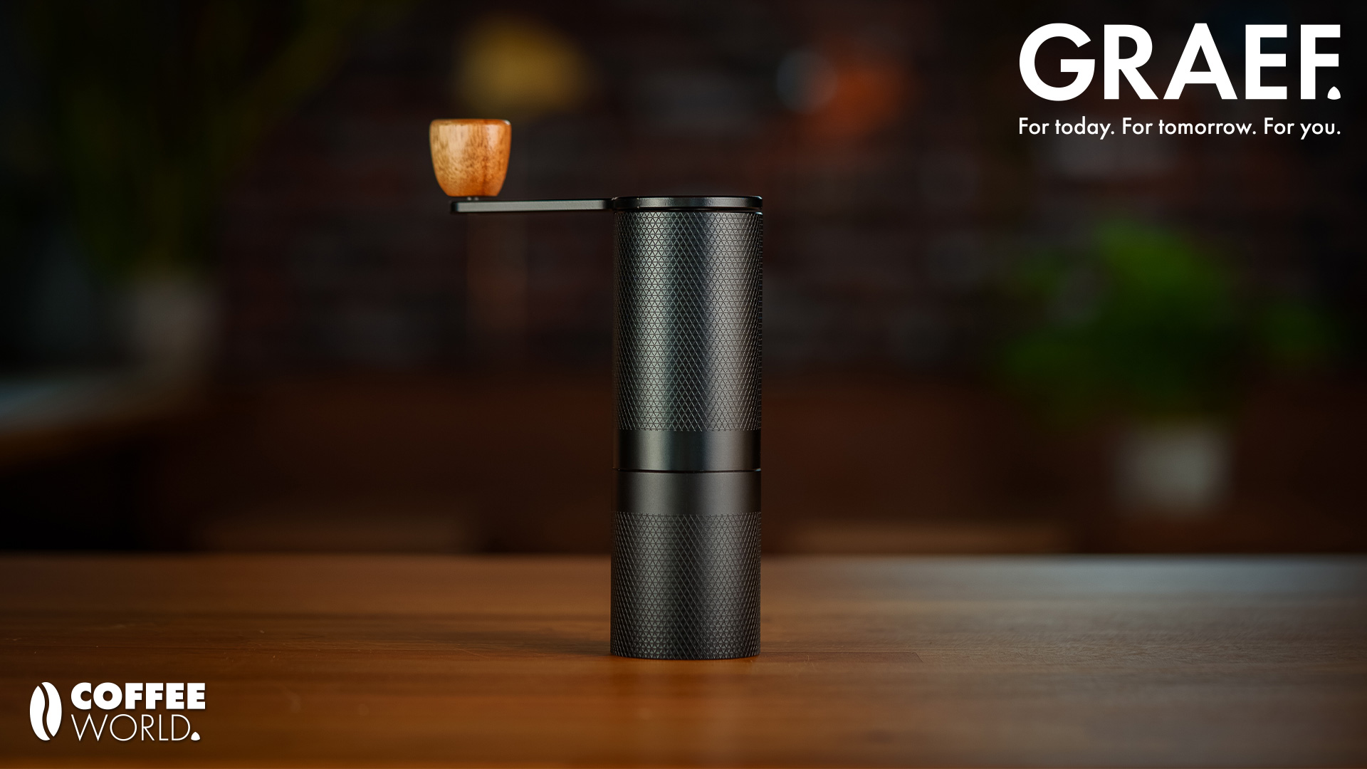 Graef coffee grinder with "Coffee World" logo on a wooden table.