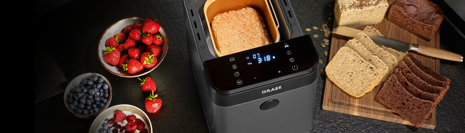 Bread maker with bread, strawberries and blueberries on a table