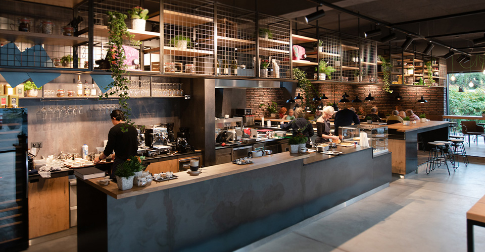 Ein modernes Café mit Bar, Küche und Gästen, gemütliche Atmosphäre.