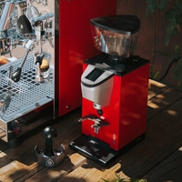 A red espresso machine and coffee grinder set on a wooden surface.