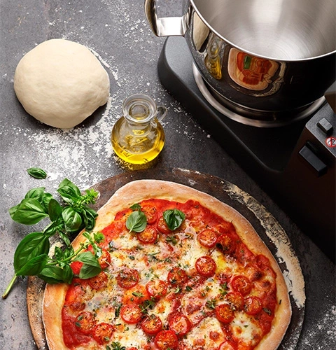 Pizza mit Zutaten, Teig, Öl und Küchenmaschine auf dem Tisch