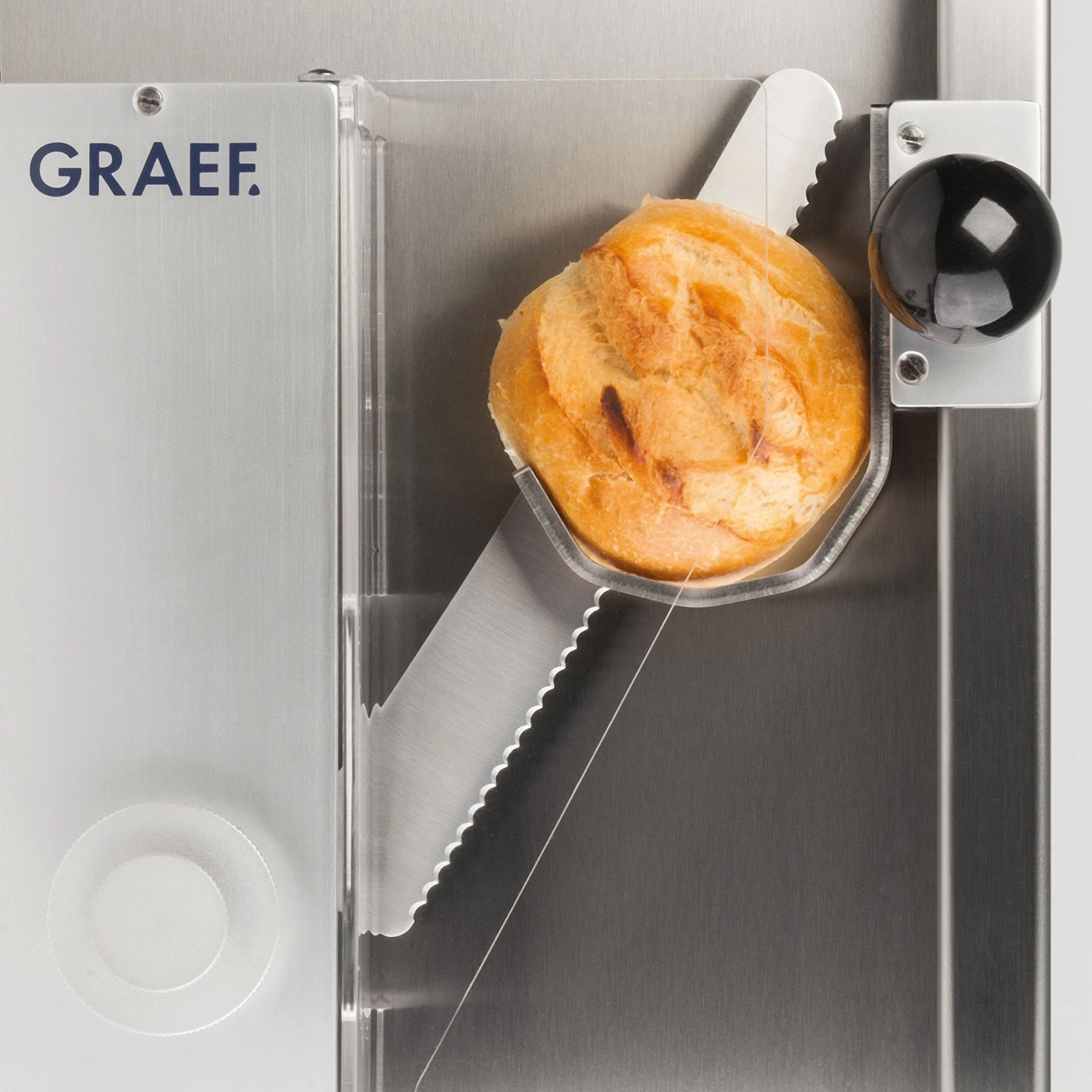 Brot in einer Brotschneidemaschine. GRAEF-Logo. Nahaufnahme. Edelstahl.