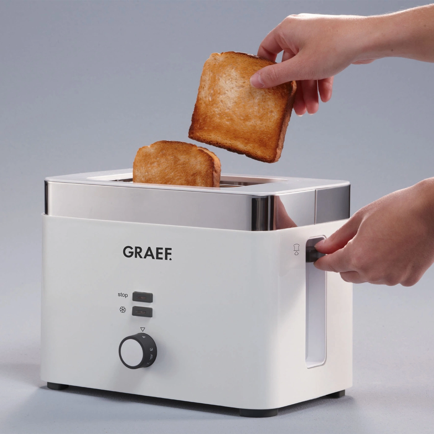 Weißer Toaster mit Toastbrot, Hände bedienen das Gerät.
