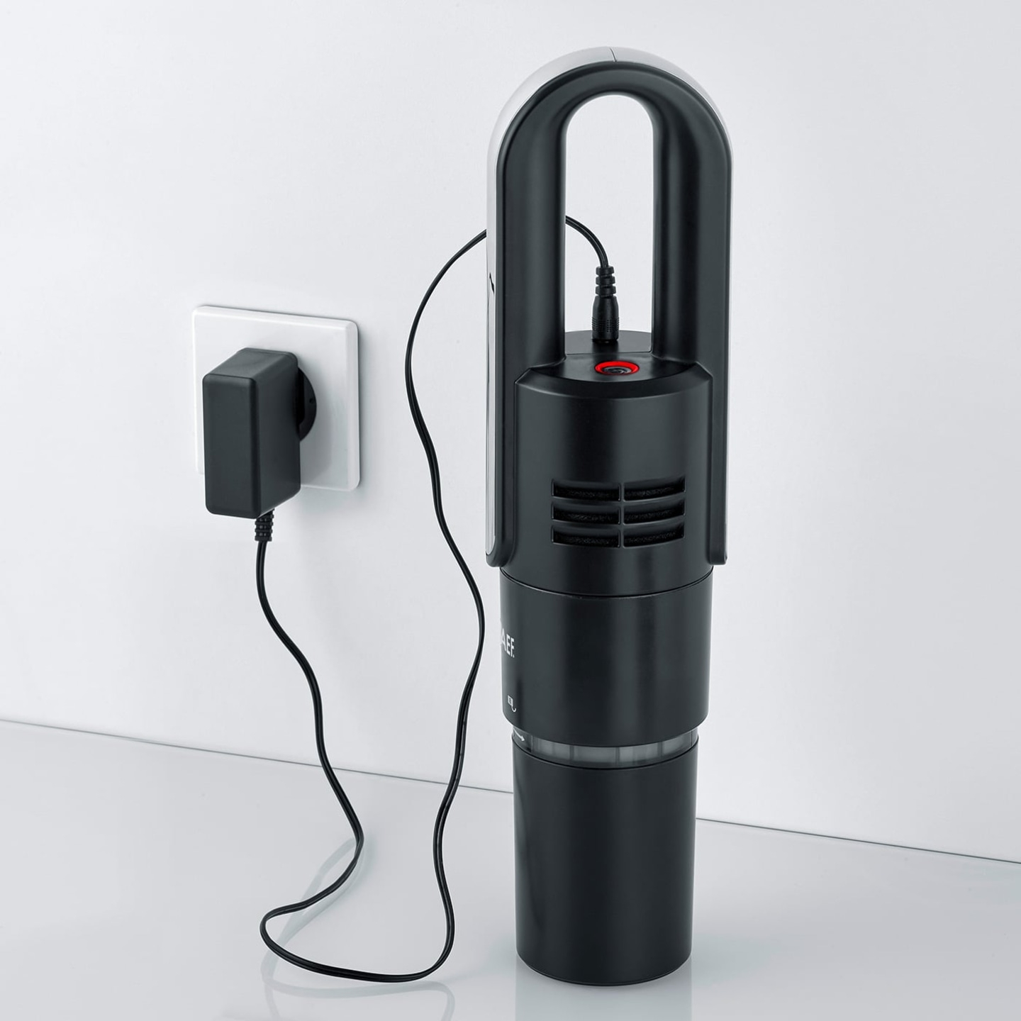 Schwarzer Staubsauger mit Ladegerät an der Wand, bereit zum Aufladen.