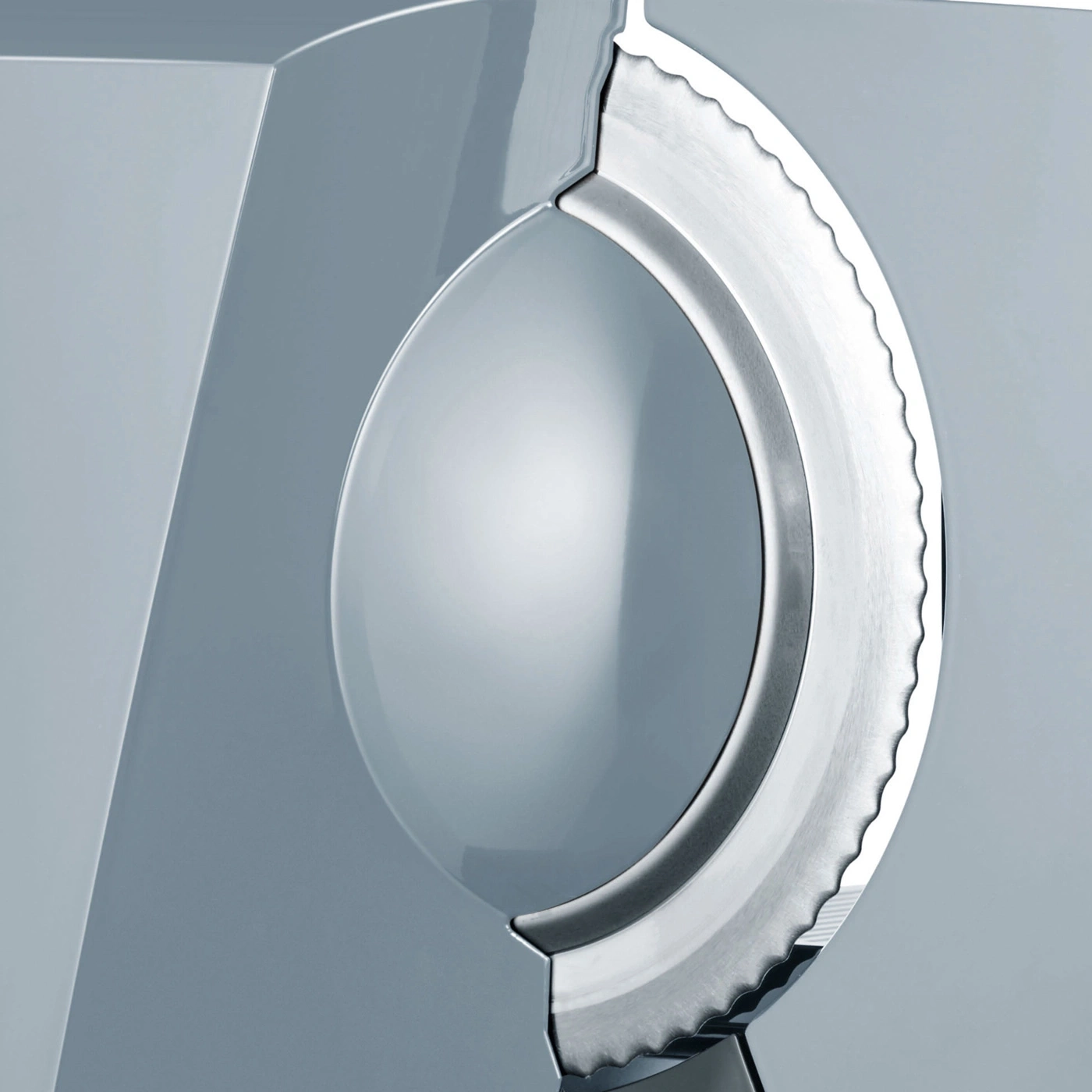 Close-up of a silver serrated blade embedded in a grey surface, with a reflective dome.