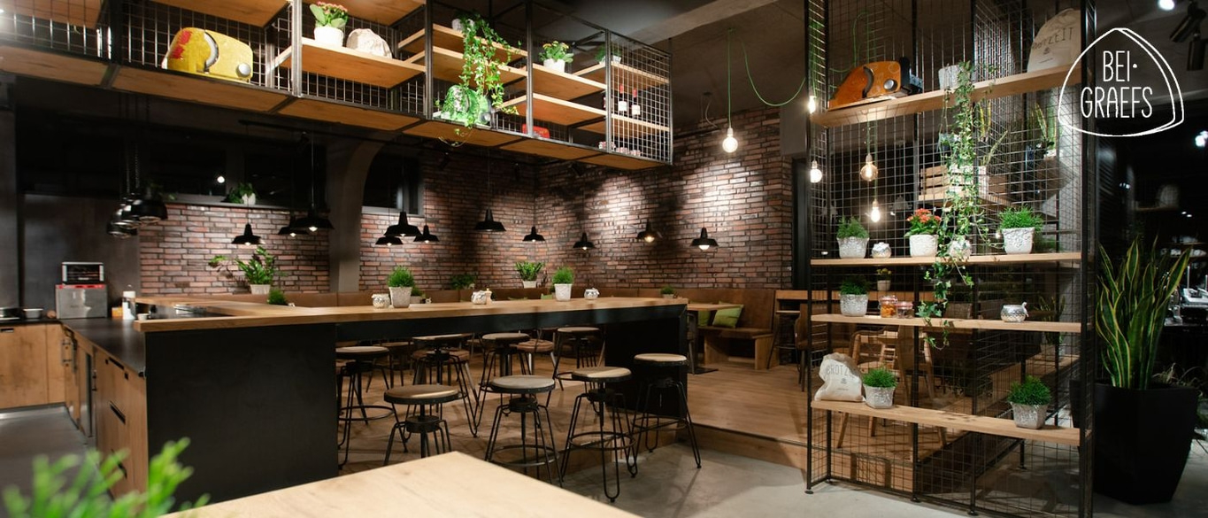 Gemütliches Restaurant mit Backsteinmauer, Pflanzen und stilvoller Einrichtung.