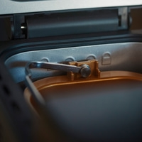 Close-up of a bread maker with golden interior and a tool inside the machine