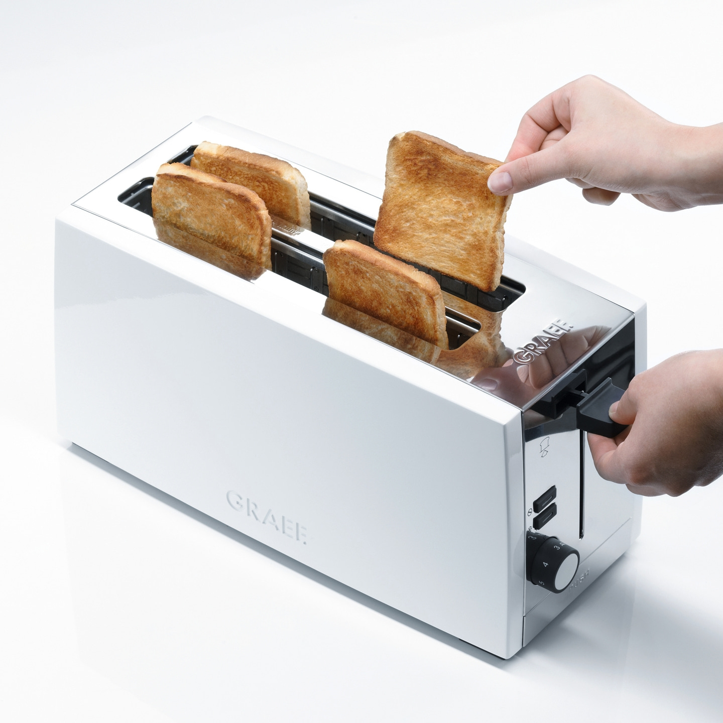 Weißer Toaster mit Toastbrot, das aus dem Toaster genommen wird.