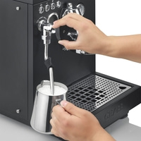 Person frothing milk with an espresso machine to make coffee.