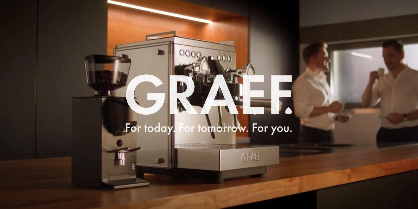 Coffee machine and grinder with two men in the background