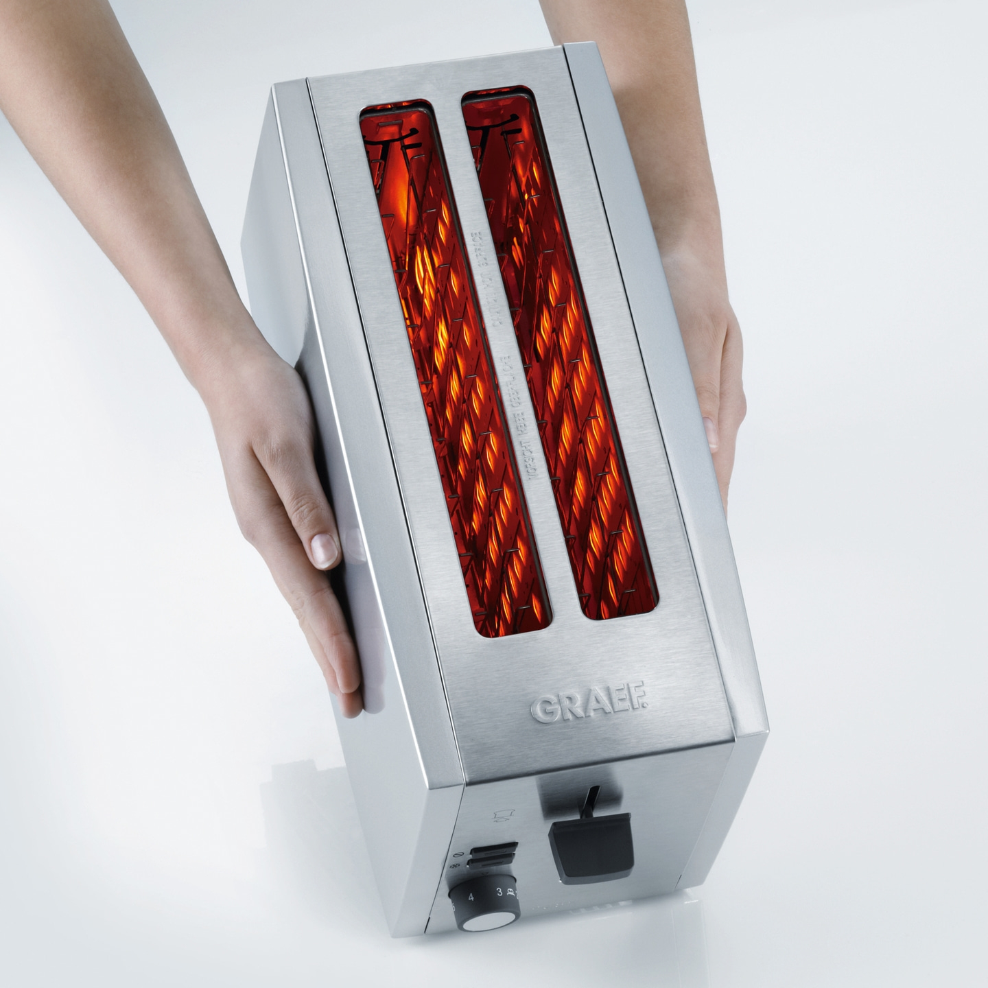Toaster mit Händen gehalten, Edelstahl, GRAEF-Logo, Toastschlitze, helles Licht