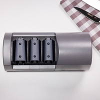 Graues Messer-Schärfgerät mit drei Schlitzen und einem Messer auf einem karierten Tuch.