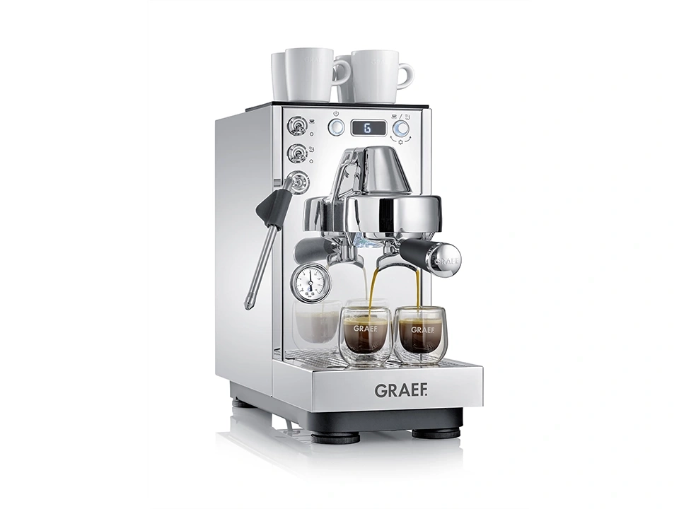 Eine glänzende Chrom-Espressomaschine mit zwei Tassen Kaffee und zwei Tassen auf der Oberseite.