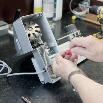 Person repariert Gerät mit Schraubendreher, Nahaufnahme, Werkstatt, Technik