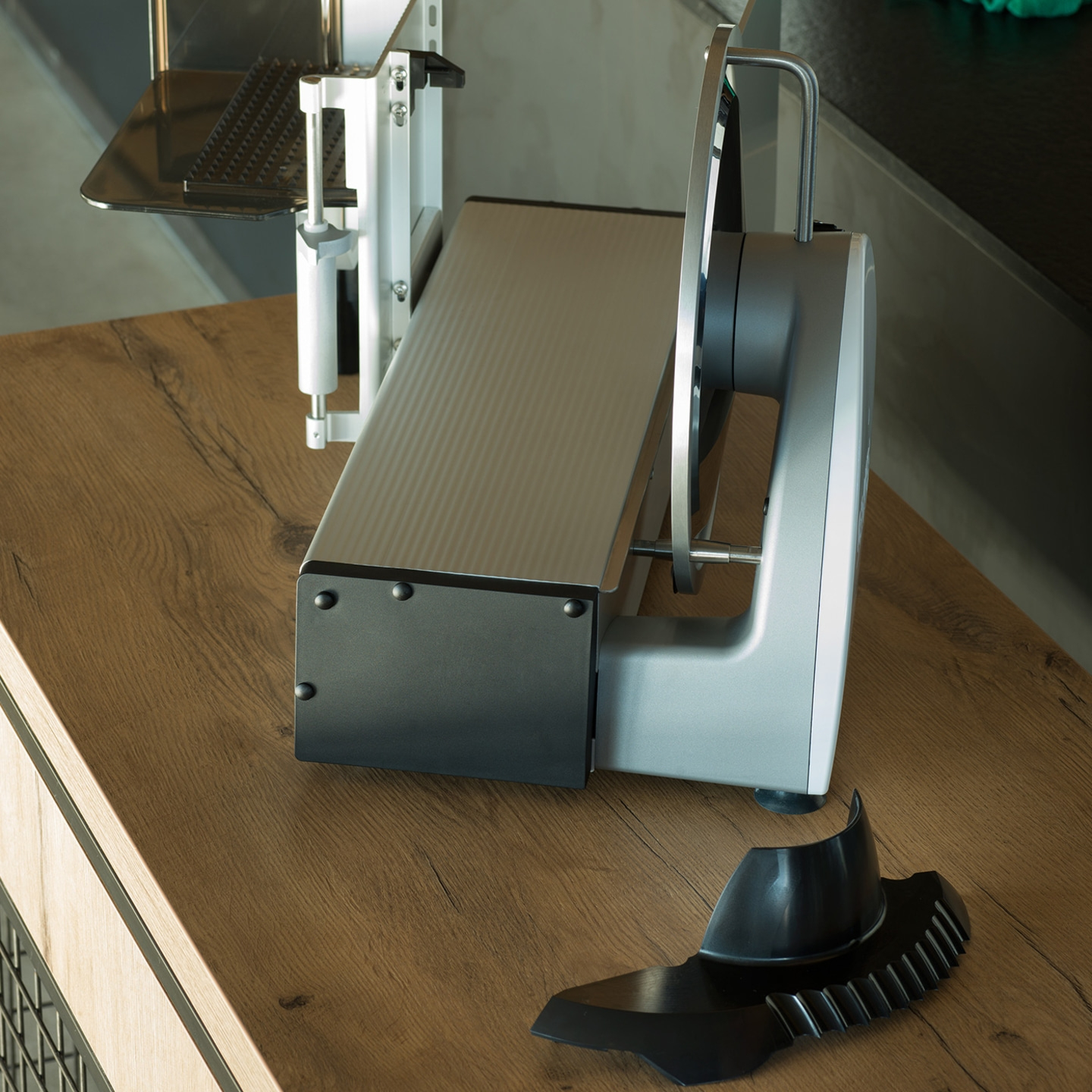 Elektrische Aufschnittmaschine auf Holzoberfläche, mit abnehmbaren Teilen.