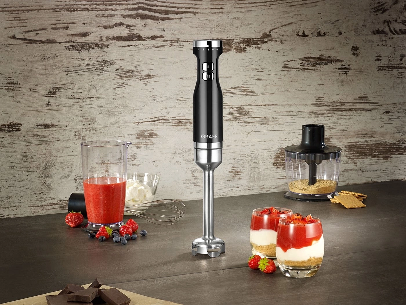 Hand blender with dessert ingredients, strawberries, chocolate, berries, glasses