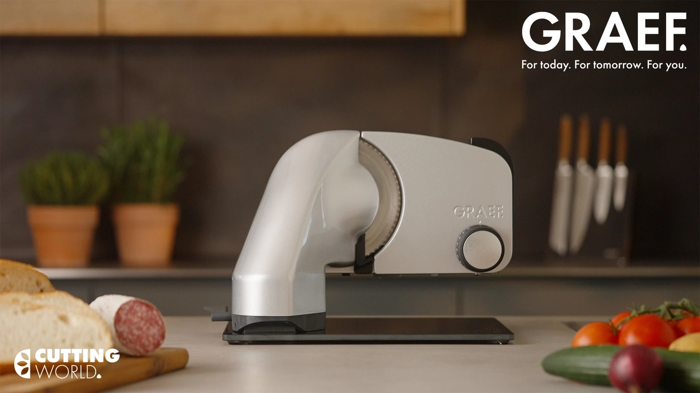 A GRAEF slicer with bread and salami on a cutting board.