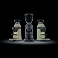Three coffee grinders in different colors against a black background.
