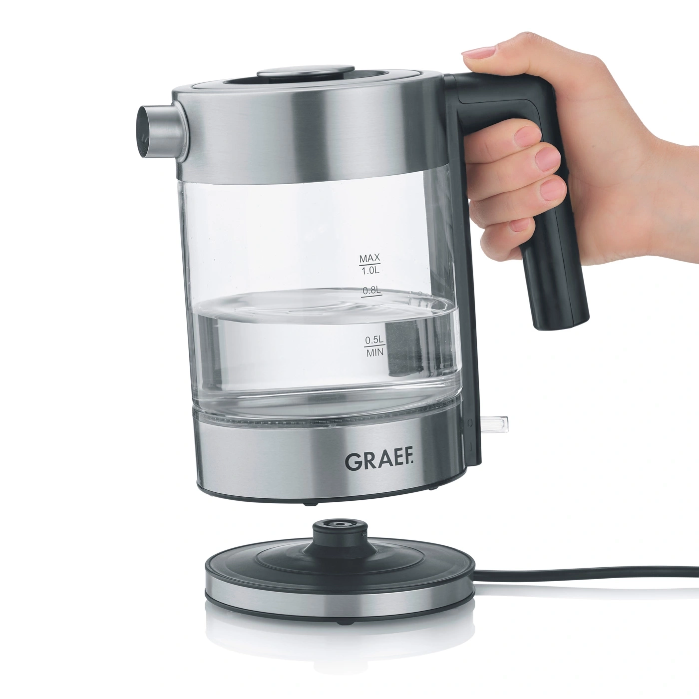 Glass and stainless steel kettle, filled with water, being held by a hand