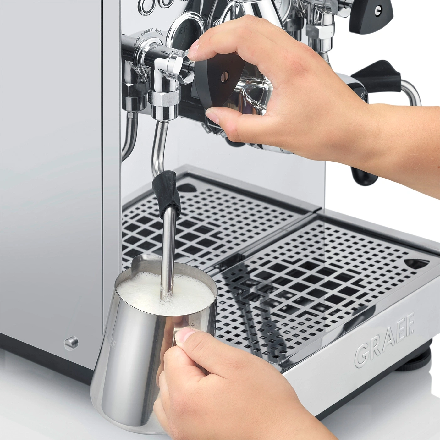Person is frothing milk with an espresso machine to make a latte.