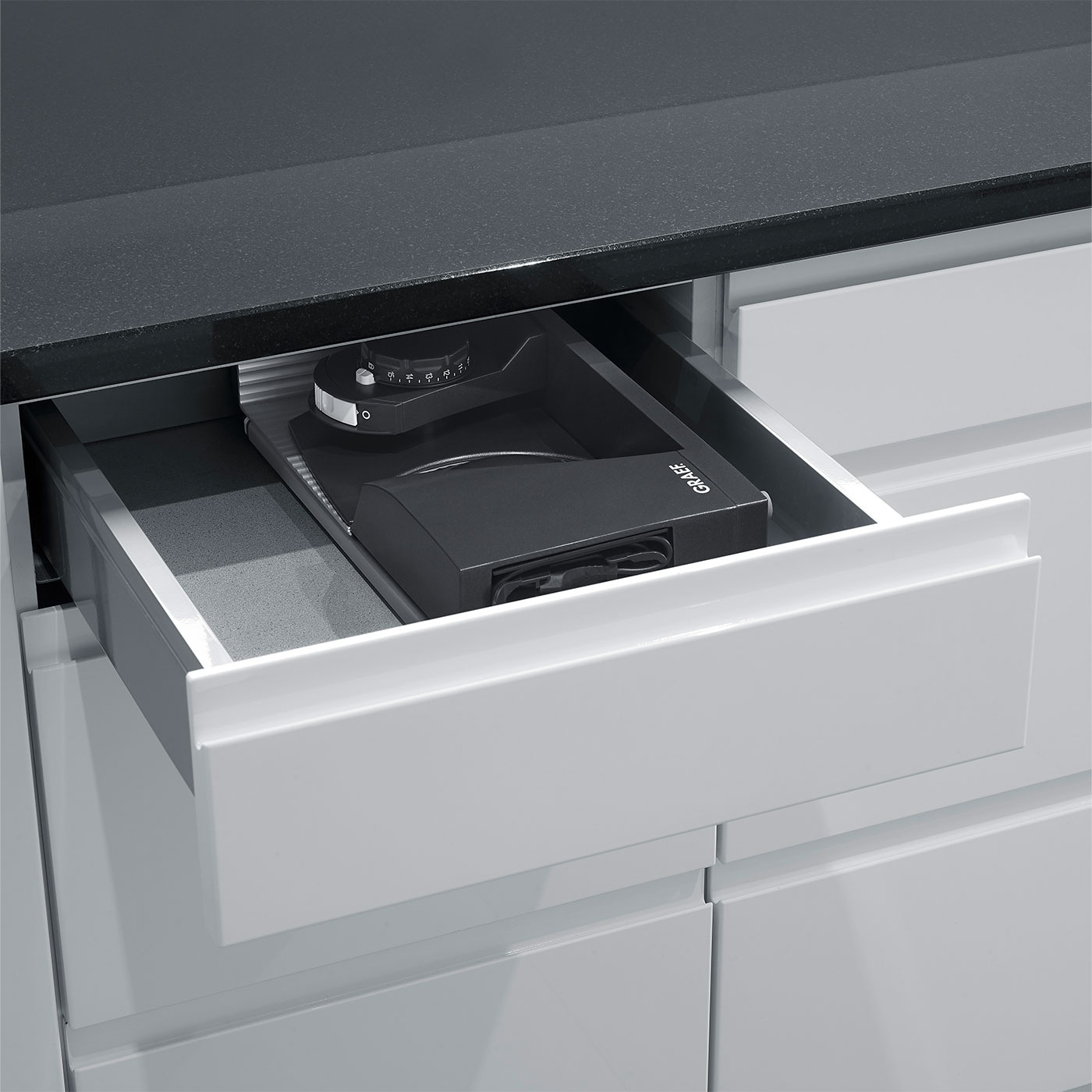 Schublade mit Kaffeemühle, schwarze Arbeitsplatte, Küchenschrank, Graef-Logo.