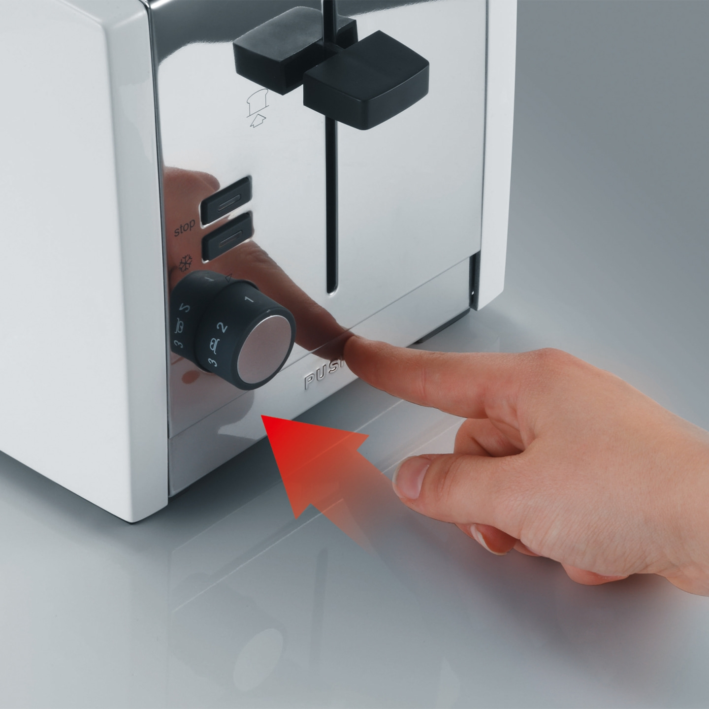 Nahaufnahme eines Toasters mit einem Finger, der auf einen Knopf zeigt.