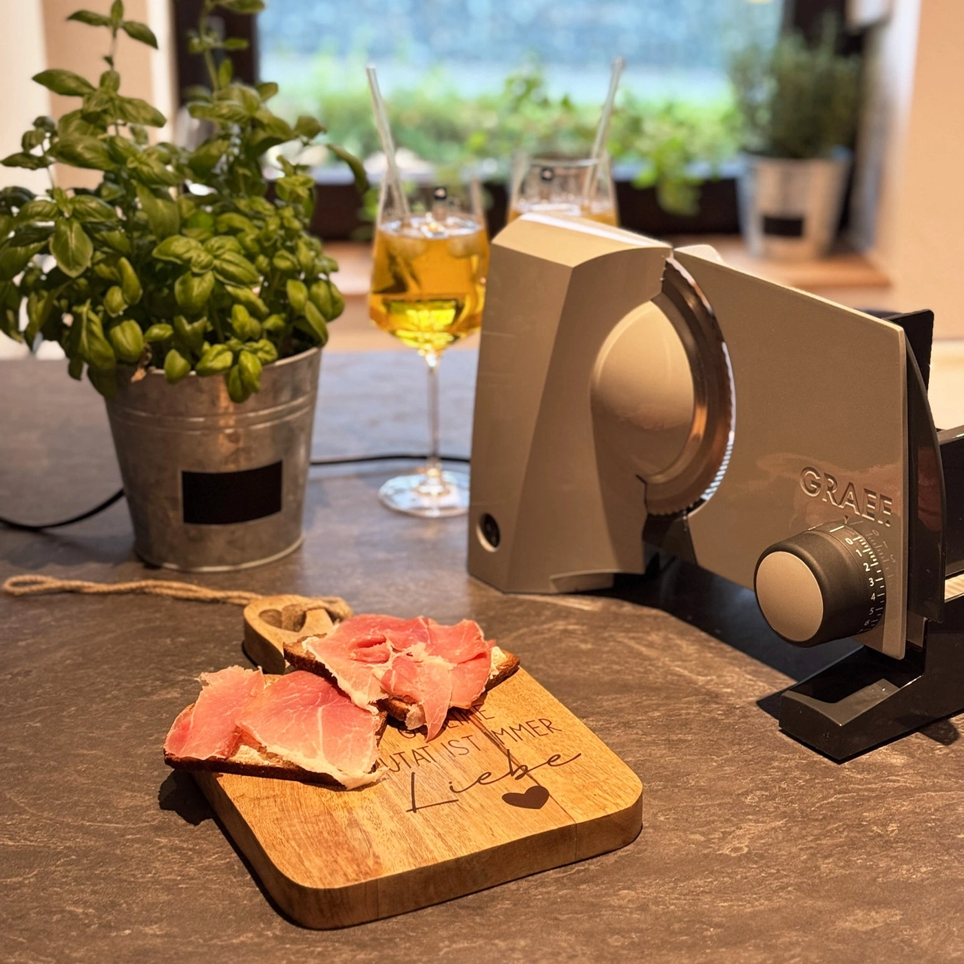 Ein Holzlöffel mit Schinken auf einem Brett, daneben ein Graef-Schneidegerät.