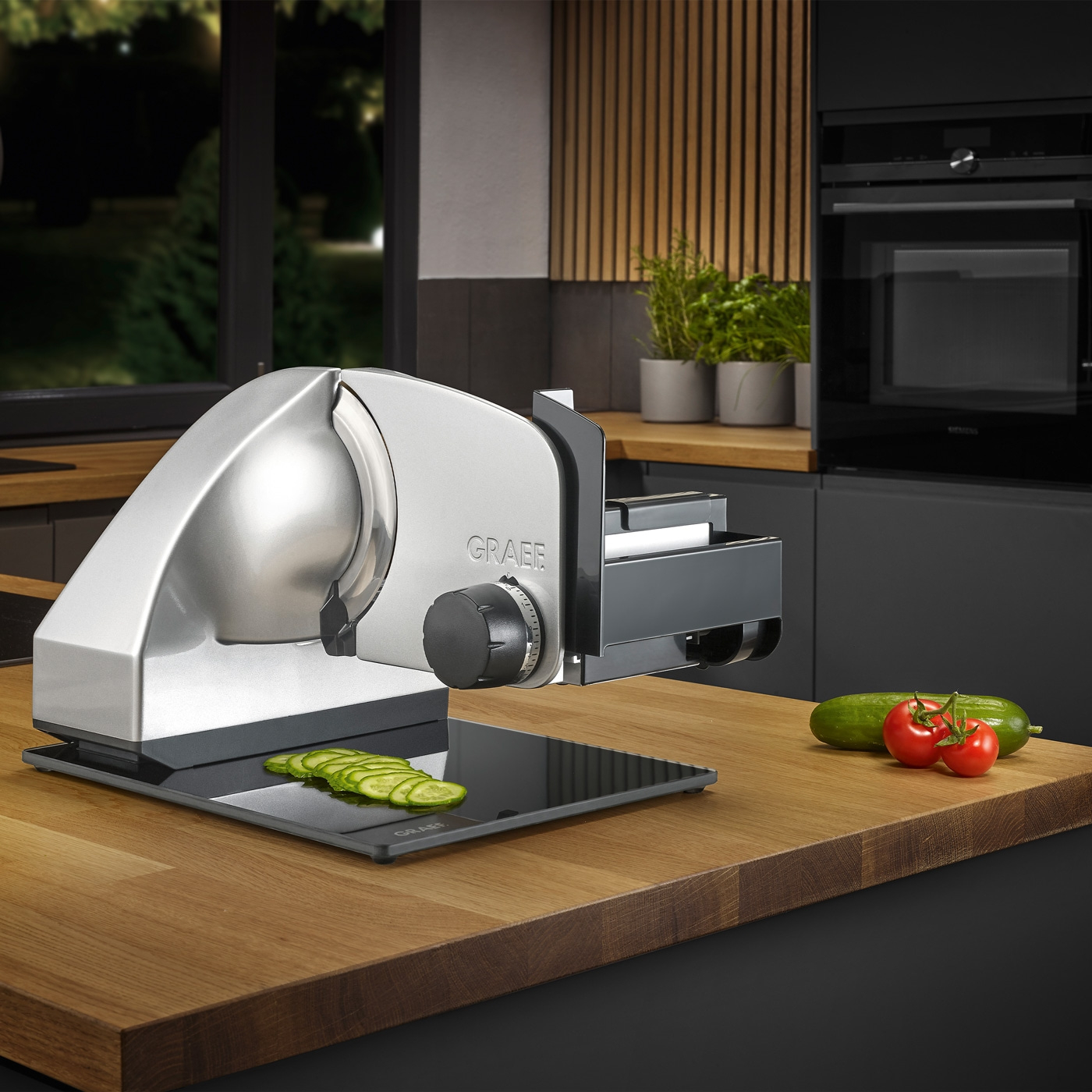 Elektrische Aufschnittmaschine mit Gemüse auf einer Holzoberfläche in einer Küche.