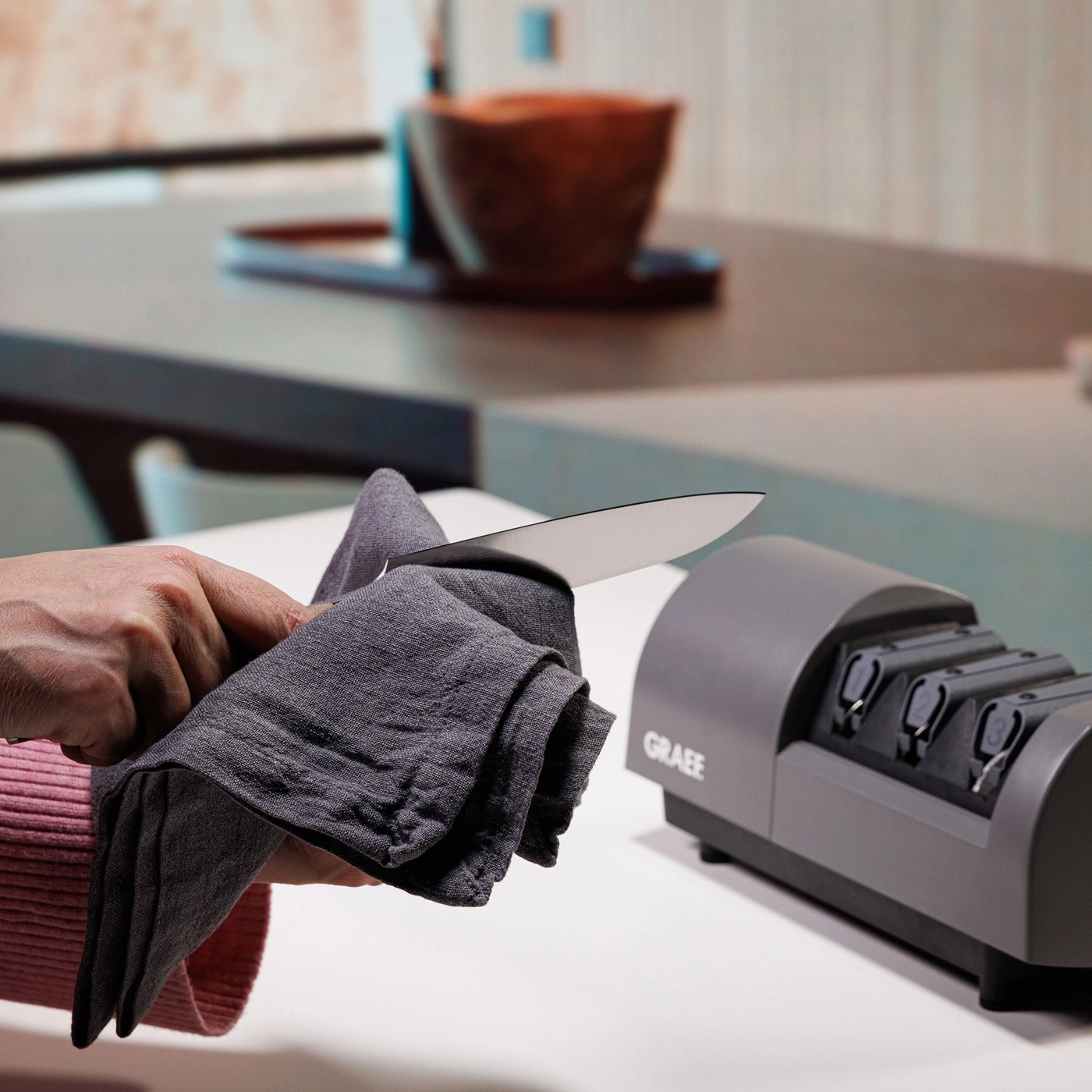 Knife being cleaned with a cloth next to a knife sharpener.