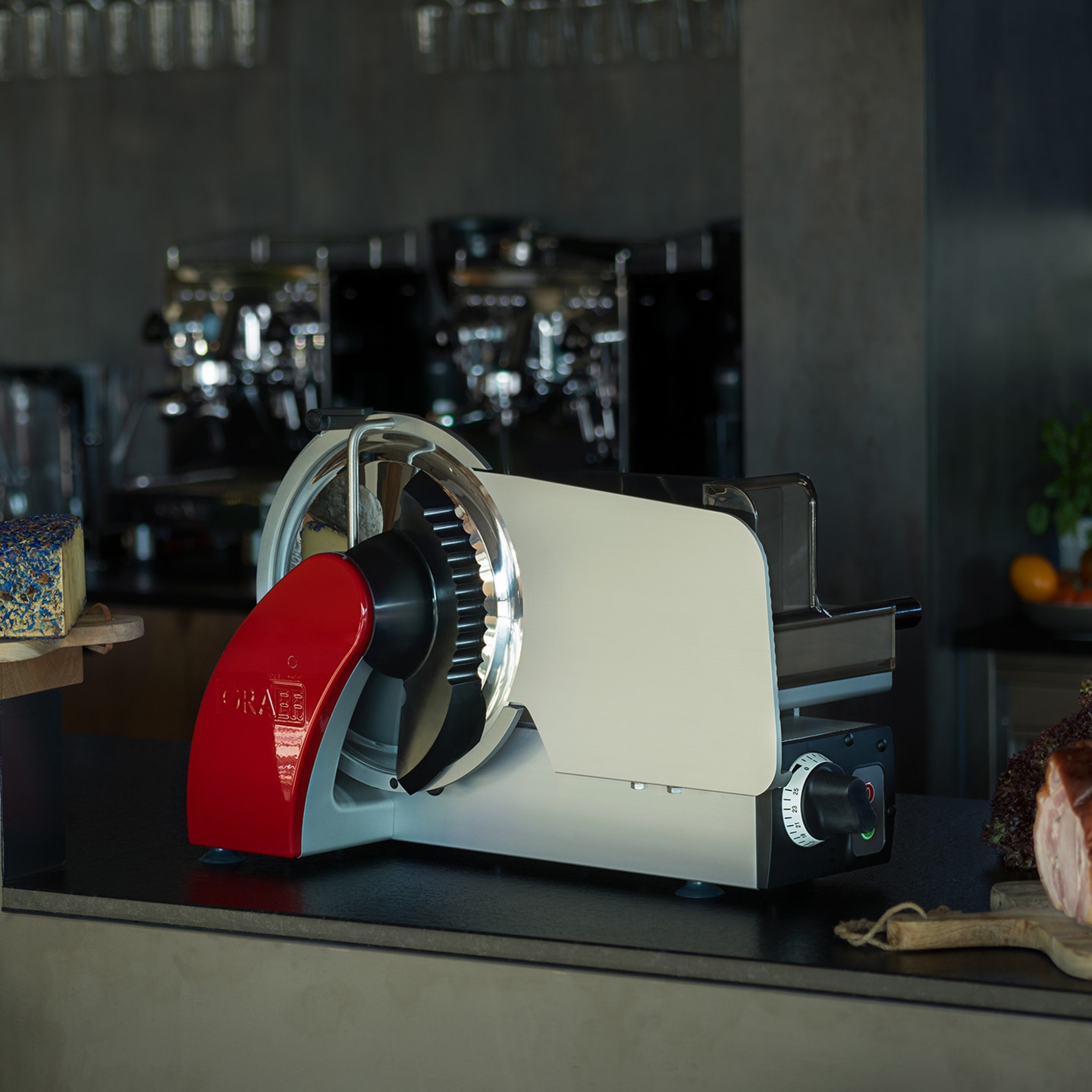 Graef Aufschnittmaschine auf einer Theke mit Käse und Fleisch im Hintergrund