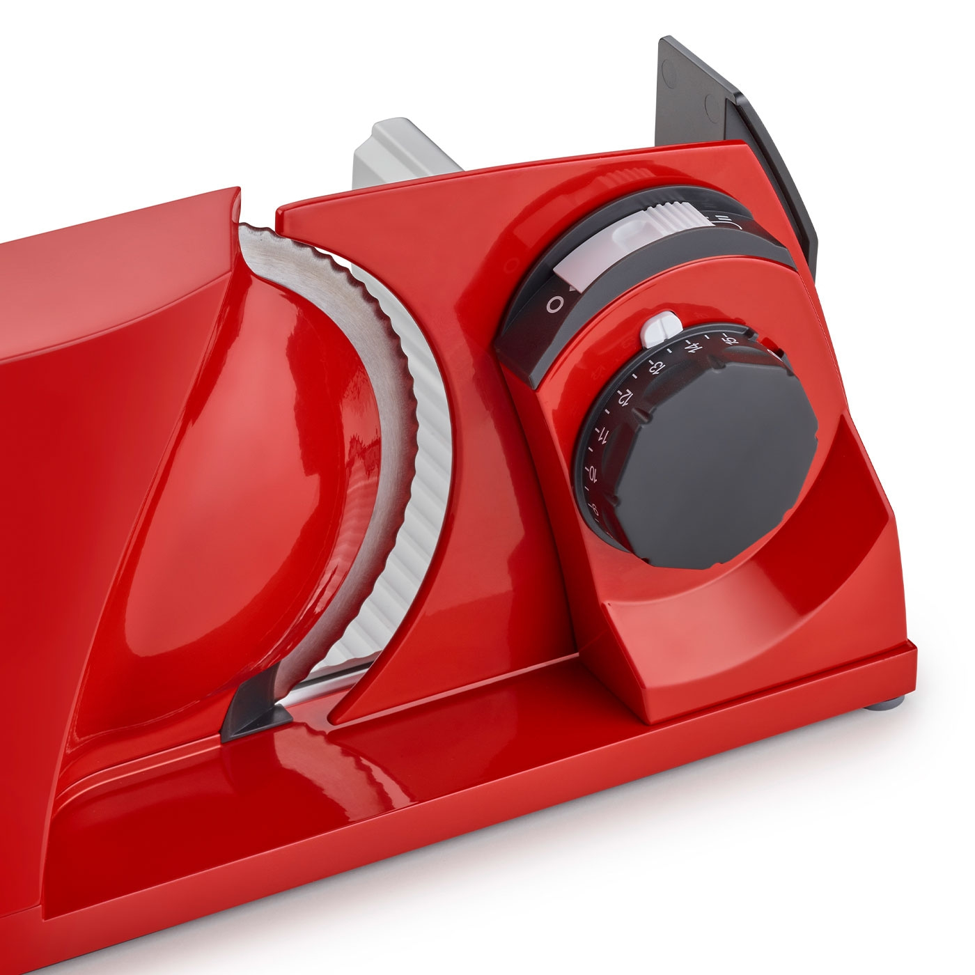 Red food slicer with black knob and blade for slicing food, close-up shot.