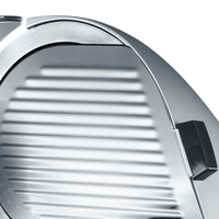 Close-up of a silver meat slicer with a black handle and a ridged surface