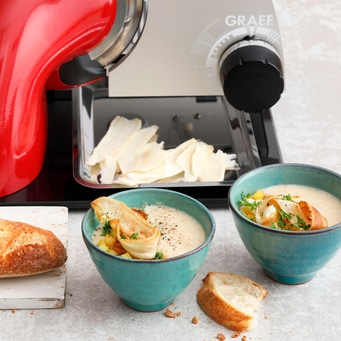 Suppe mit Brot und Gemüse, serviert mit einer Schneidemaschine.