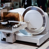 Fleischschneidemaschine mit Brot. Edelstahl, professionell, Küche, Lebensmittel.