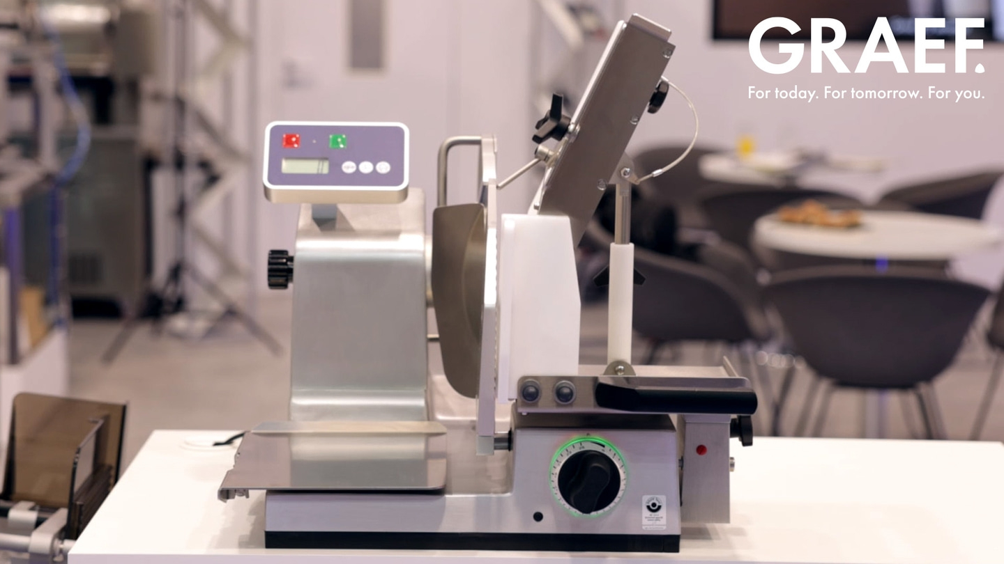 A Graef meat slicer on a table, ready to slice meat for food preparation.
