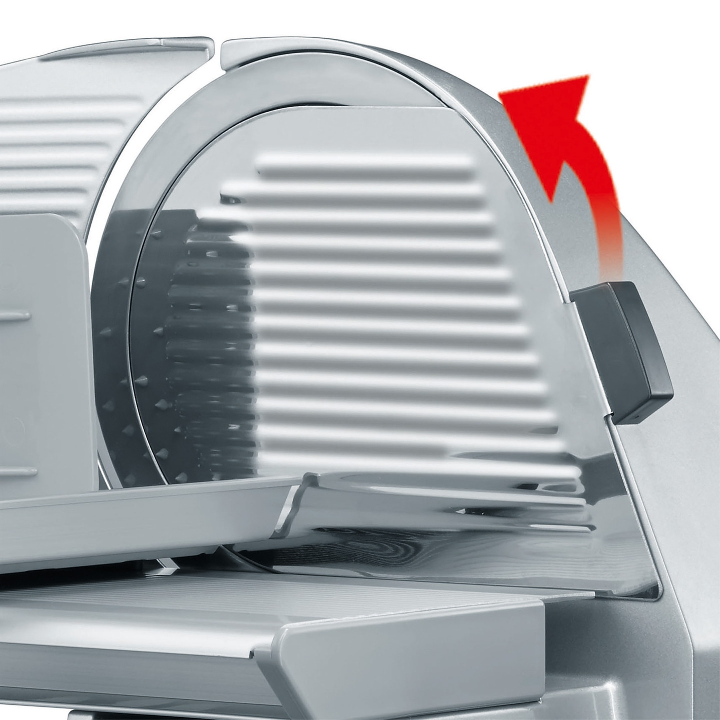 Close-up of a silver meat slicer with a red arrow indicating the movement of the blade.