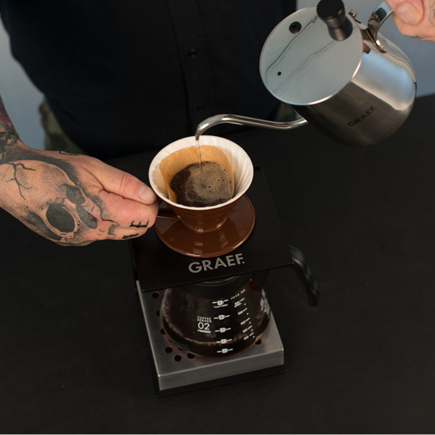 Person gießt Kaffee in einen Filter, der auf einer Kaffeemaschine steht.
