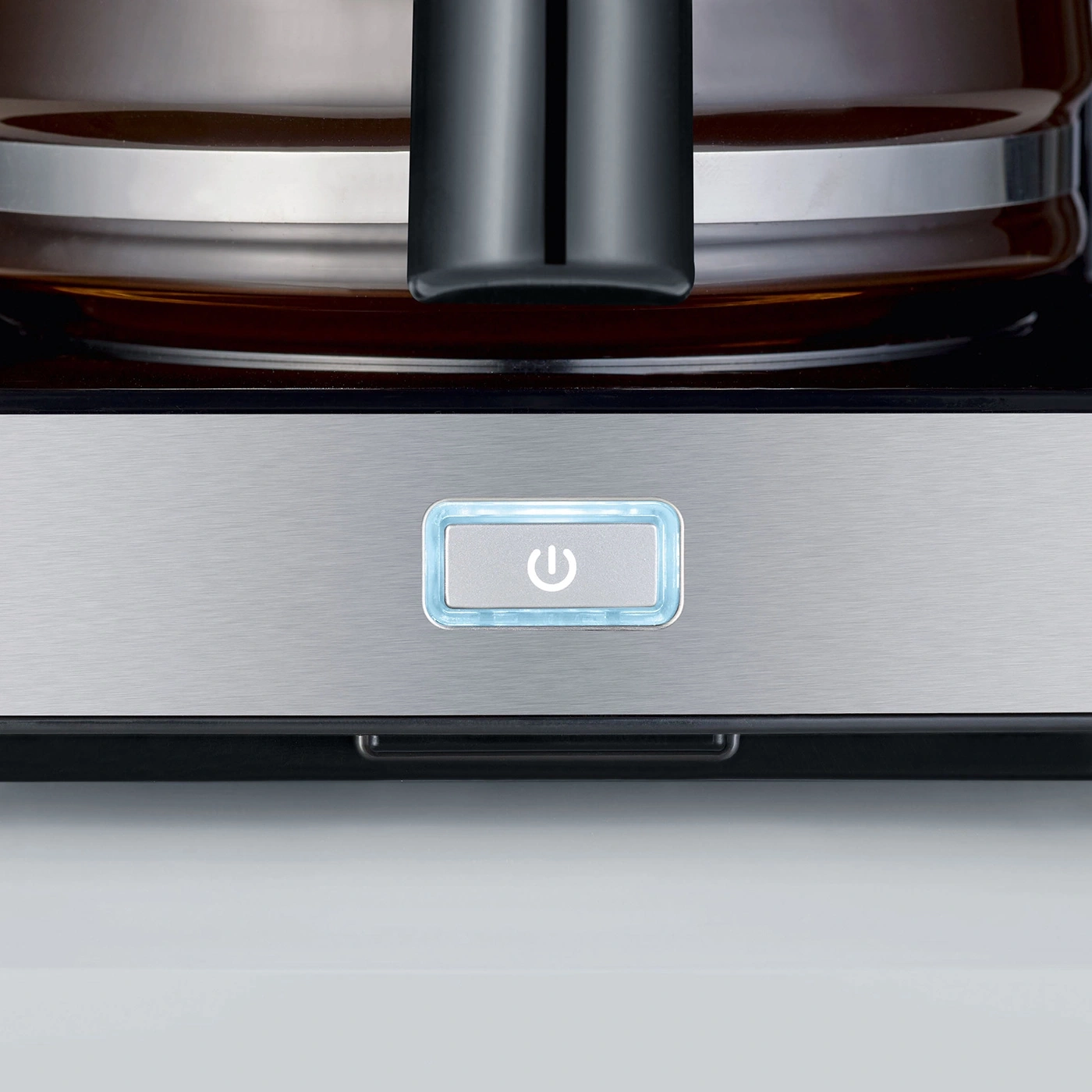 Close-up of a coffee machine with an illuminated power button