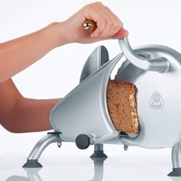 Person schneidet Brot mit einer Brotschneidemaschine, Nahaufnahme, Graet Logo