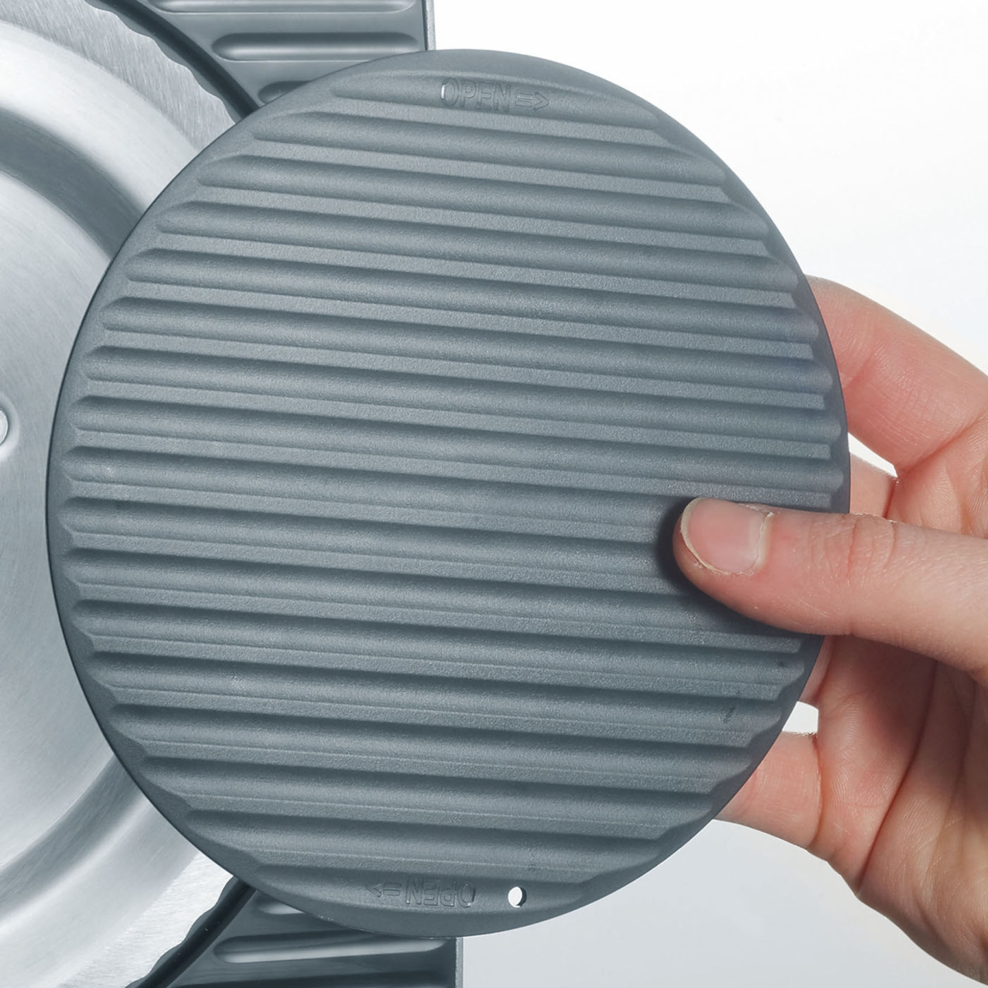 Graue runde Scheibe mit Rillen, gehalten von einer Hand, mit 'OPEN' Markierung.