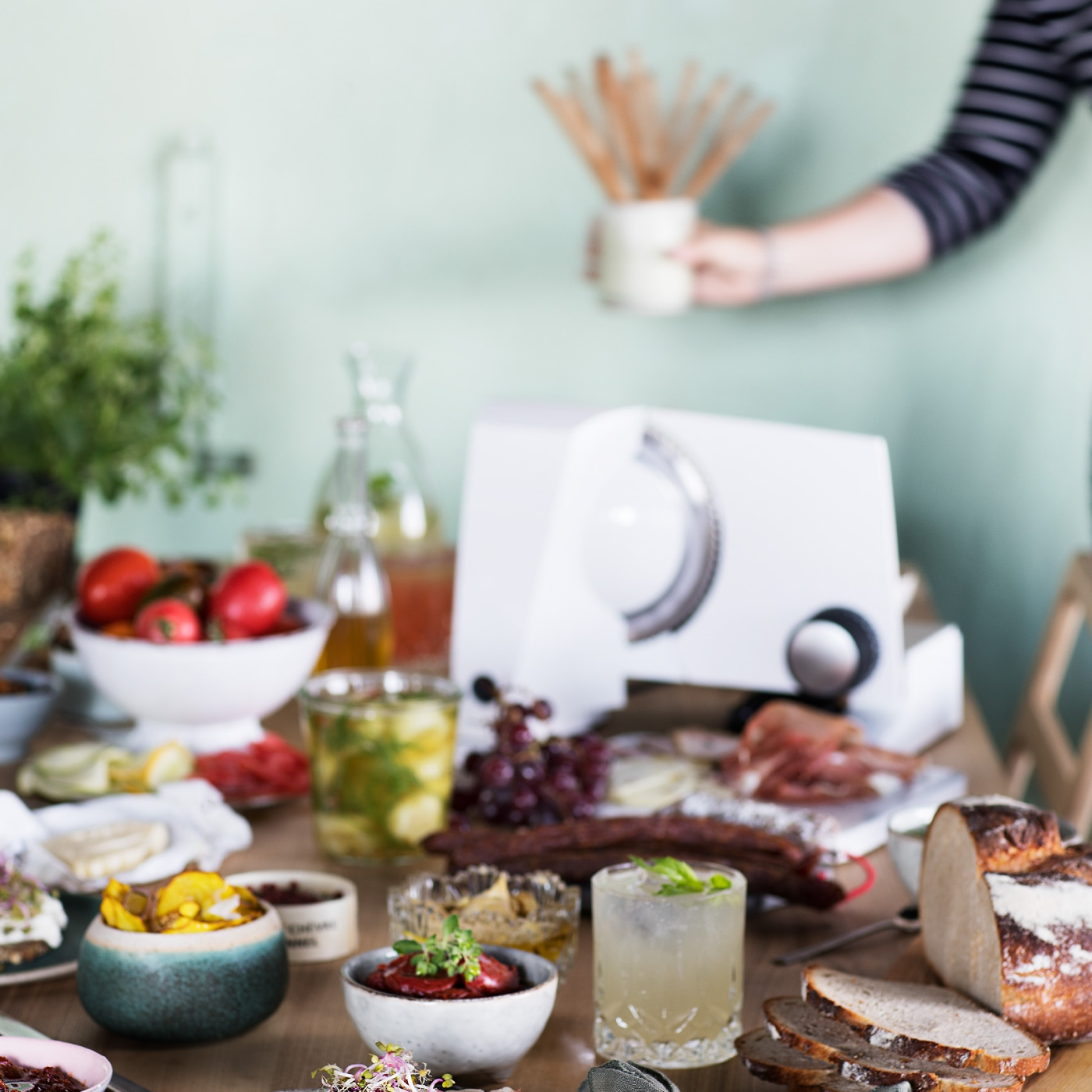 Tisch mit Essen, Getränken und einer Person, die etwas hält.