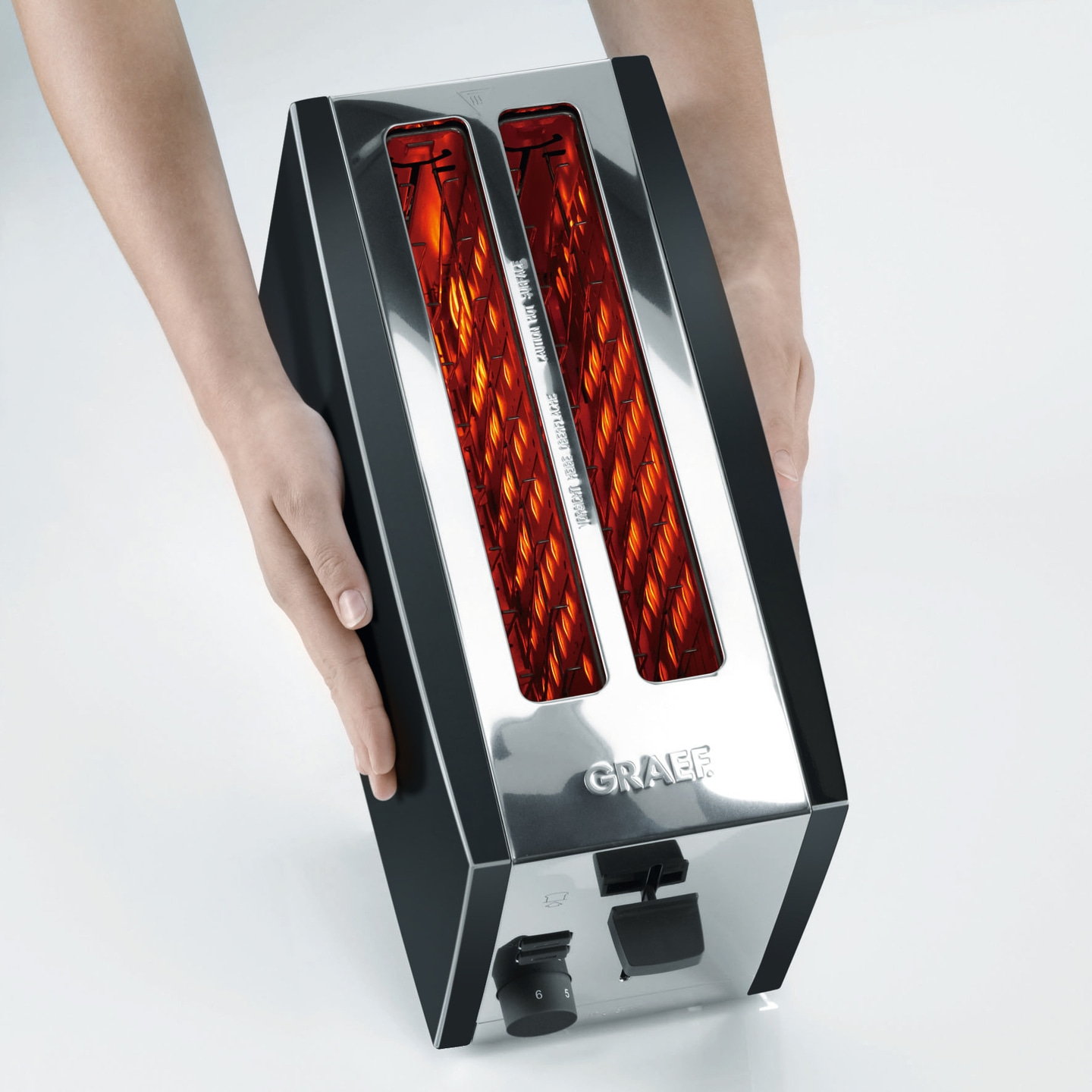 Ein Toaster wird von Händen gehalten, die das Gerät präsentieren. Glänzendes Metall und schwarzer Rahmen.