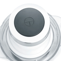Close-up of a kitchen appliance with a gray button and a white ring around it.