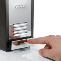 Hand drückt auf silberne Taste mit der Aufschrift "PUSH" an einem Gerät