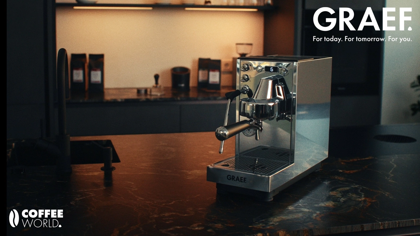 A shiny GRAEF espresso machine sits on a marble countertop in a modern kitchen.