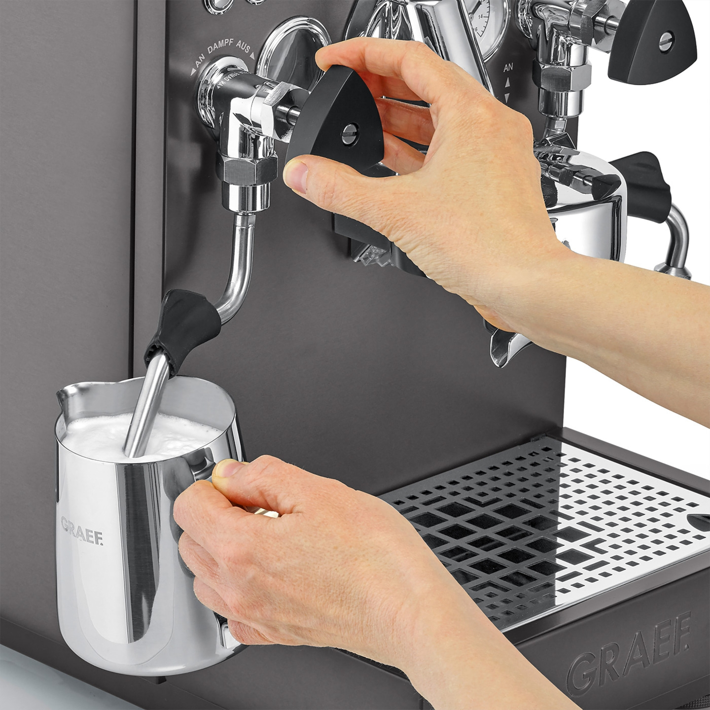 Person bereitet Milch auf einer Kaffeemaschine zu, um Kaffee zuzubereiten.